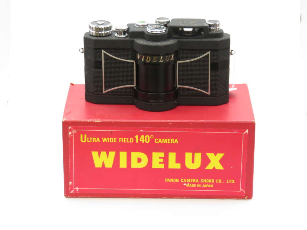A vintage Widelux camera with a wide-angle lens, placed on a red box displaying the words "ULTRA WIDE FIELD 140° CAMERA."