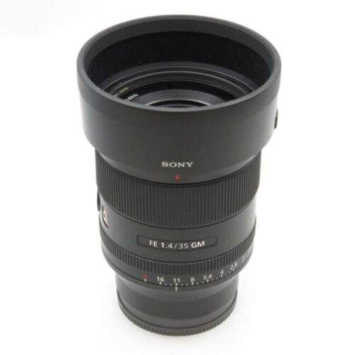 A Sony FE 35mm F1.4 GM camera lens with a black, cylindrical body and detailed focus and aperture rings.