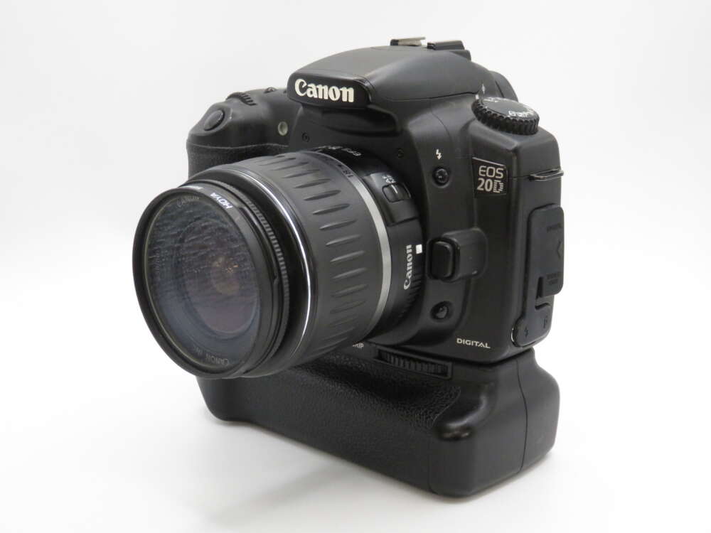 IMG_4169 A Canon EOS 20D DSLR camera with an attached zoom lens, positioned against a plain white background.