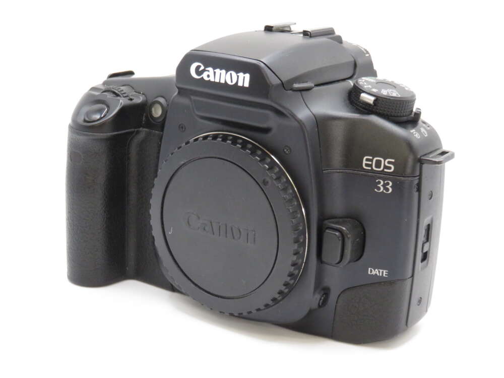IMG_4183 A Canon EOS 33 camera body with a lens cap, featuring dial controls and a textured grip.
