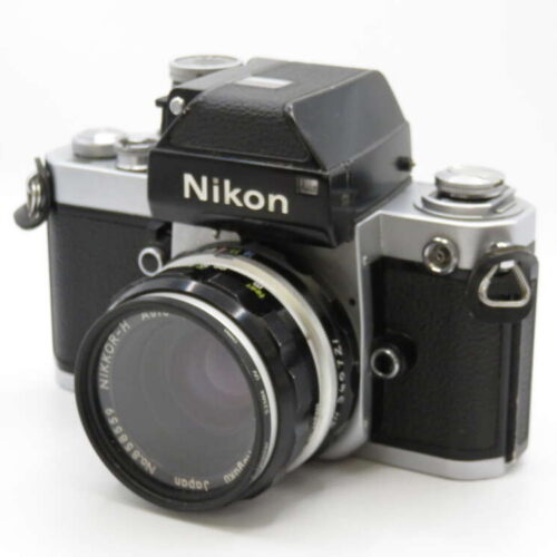 A vintage Nikon film camera with a black and silver body, featuring a Nikon lens with visible text detailing focal length.