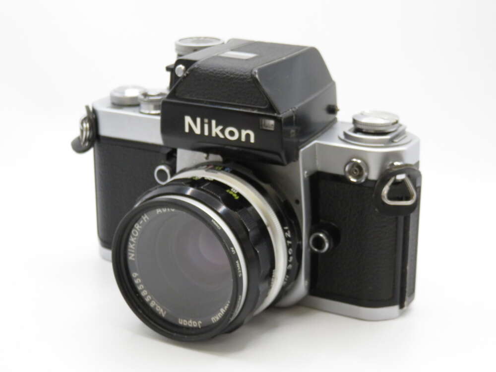 IMG_4230 A vintage Nikon film camera with a black and silver body, featuring a Nikon lens with visible text detailing focal length.