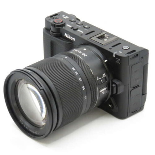A Nikon camera with a large attached zoom lens, featuring control buttons and dials on the body.