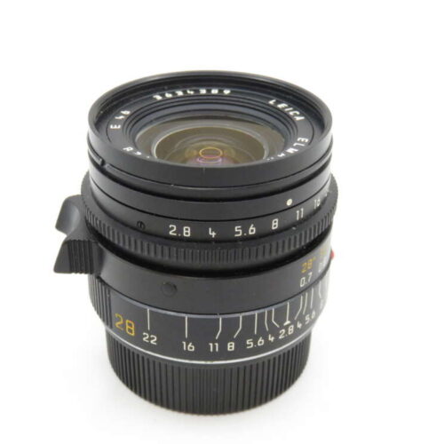 A black camera lens with manual focus and aperture rings, featuring visible focal length and aperture markings.