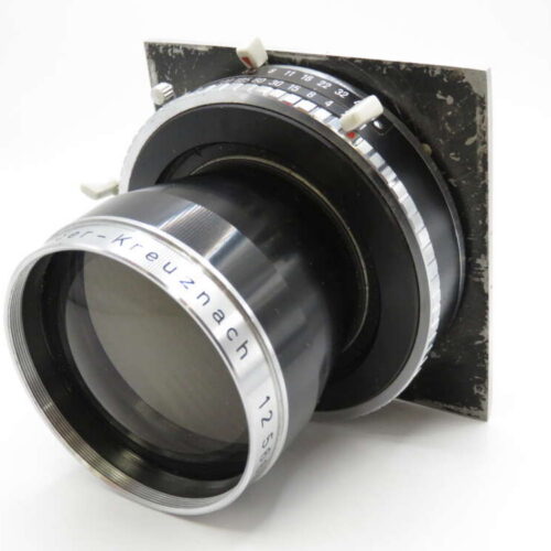 A vintage camera lens with silver and black accents, mounted on a metal plate, featuring control dials and engraved text.