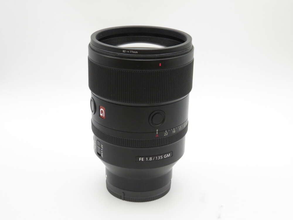 IMG_4264 A black camera lens with a wide focus ring and a red emblem, labelled "FE 1.8/135 GM," on a plain white background.