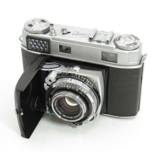 A vintage camera with a silver and black body and a lens with multiple dials and settings visible.