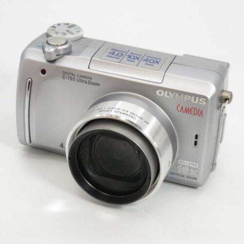 A silver Olympus Camedia C-765 Ultra Zoom digital camera with a prominent lens and several control dials on top.