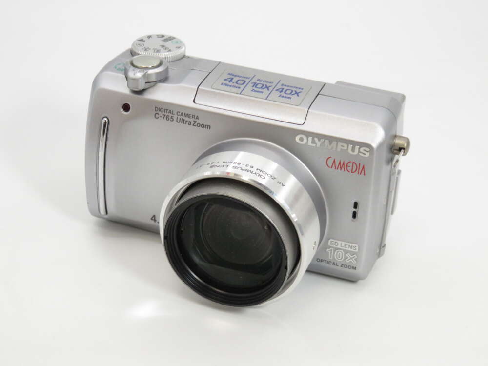 IMG_4290 A silver Olympus Camedia C-765 Ultra Zoom digital camera with a prominent lens and several control dials on top.