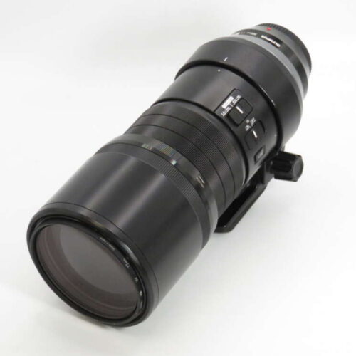 A large black camera lens with a tripod mount and various control switches on a white background.