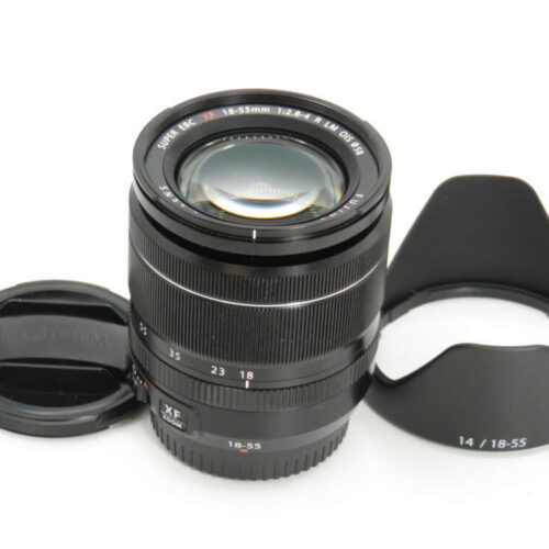 A Fujifilm XF 18-55mm camera lens with its front lens cap removed and a petal-shaped lens hood beside it.