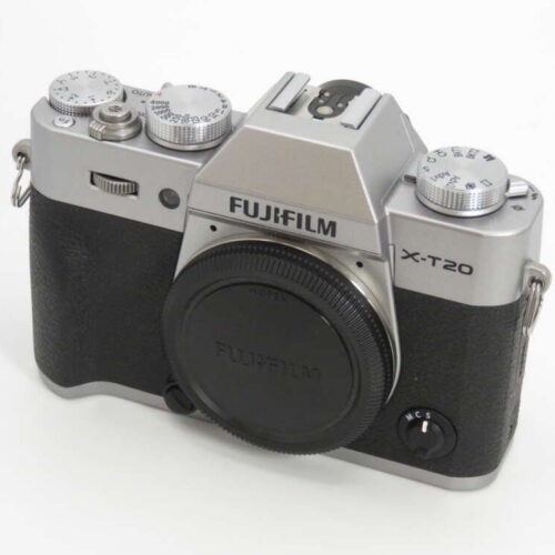 A Fujifilm X-T20 camera with a silver top and black body, featuring dials and a lens cap.