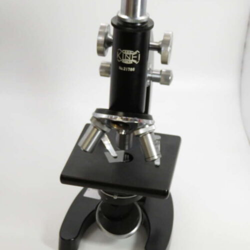 Black vintage microscope with multiple adjustment knobs and a labelled model number "21786" on a white background.